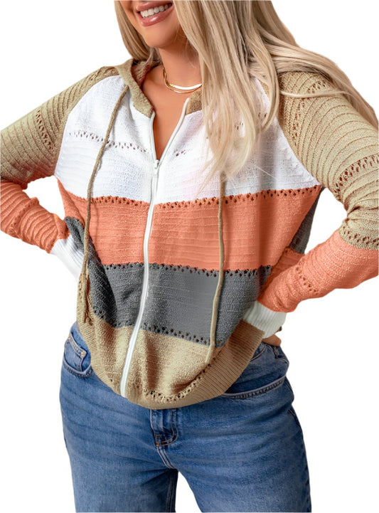 Woman wearing a color-block hooded zip-up sweater with earthy tones of beige, rust, gray, and white