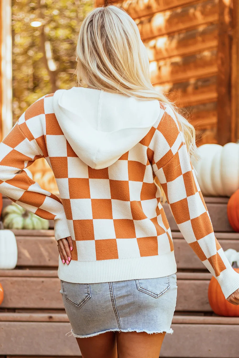 Orange and white checkered sweater with a hood, featuring a front pocket and long sleeves.
