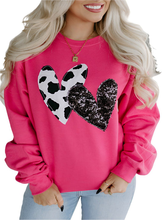 Woman wearing hot pink cow sweatshirt with cow print heart and sequin heart design
