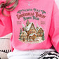 Bright hot pink sweatshirt with gingerbread house design, adding holiday cheer.