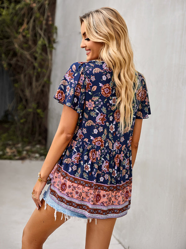 Woman wearing a navy blue floral peplum top with tassels, styled with denim shorts.