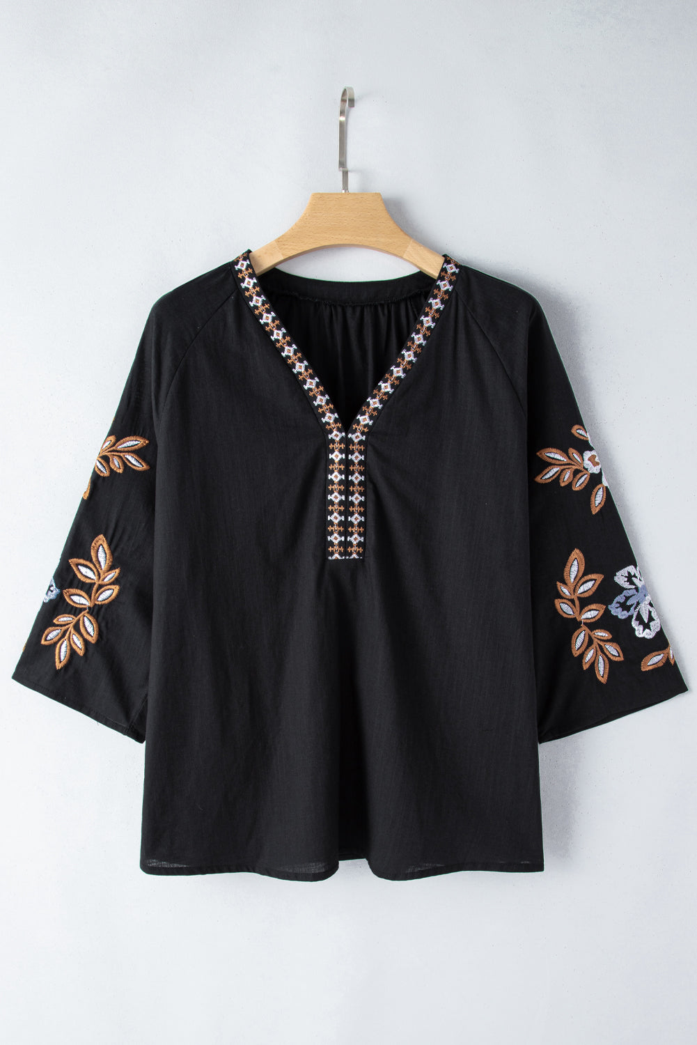 Close-up of floral embroidery on a black boho blouse with relaxed sleeves