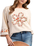 Woman wearing an ivory floral applique blouse with exposed seams and a relaxed fit.
