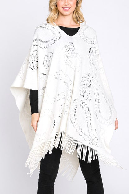 Ivory paisley perforated knit poncho with fringe hem, front view.
