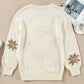 Flat-lay of an ivory knit sweater featuring a snowflake design, ideal for a cozy holiday look.