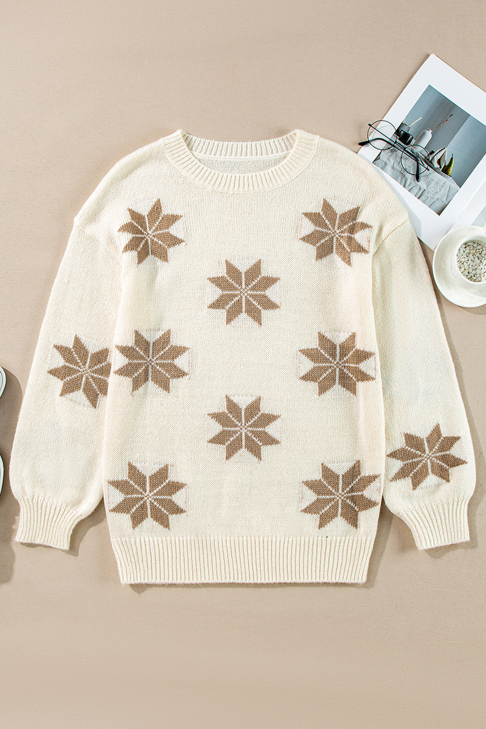 Flat-lay of an ivory knit sweater featuring a snowflake design, ideal for a cozy holiday look.