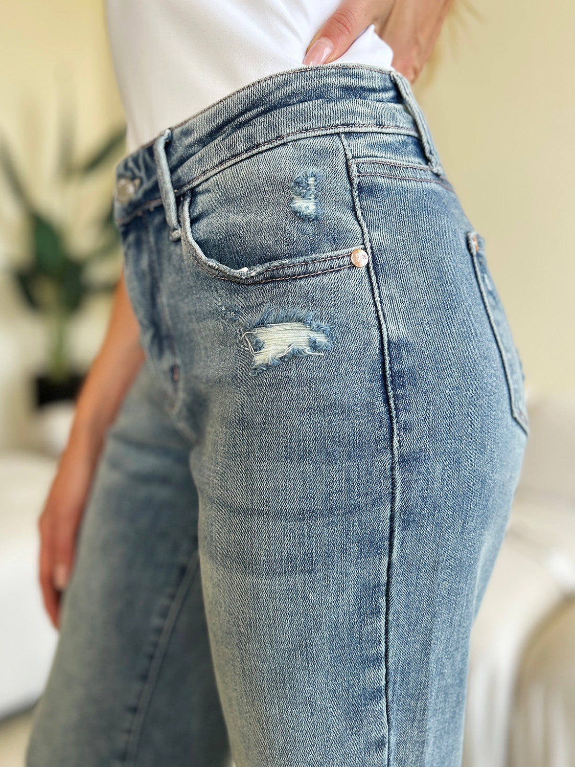 Detailed view of the distressing on the front thigh of the Judy Blue Mid Rise Distressed Straight Jeans.