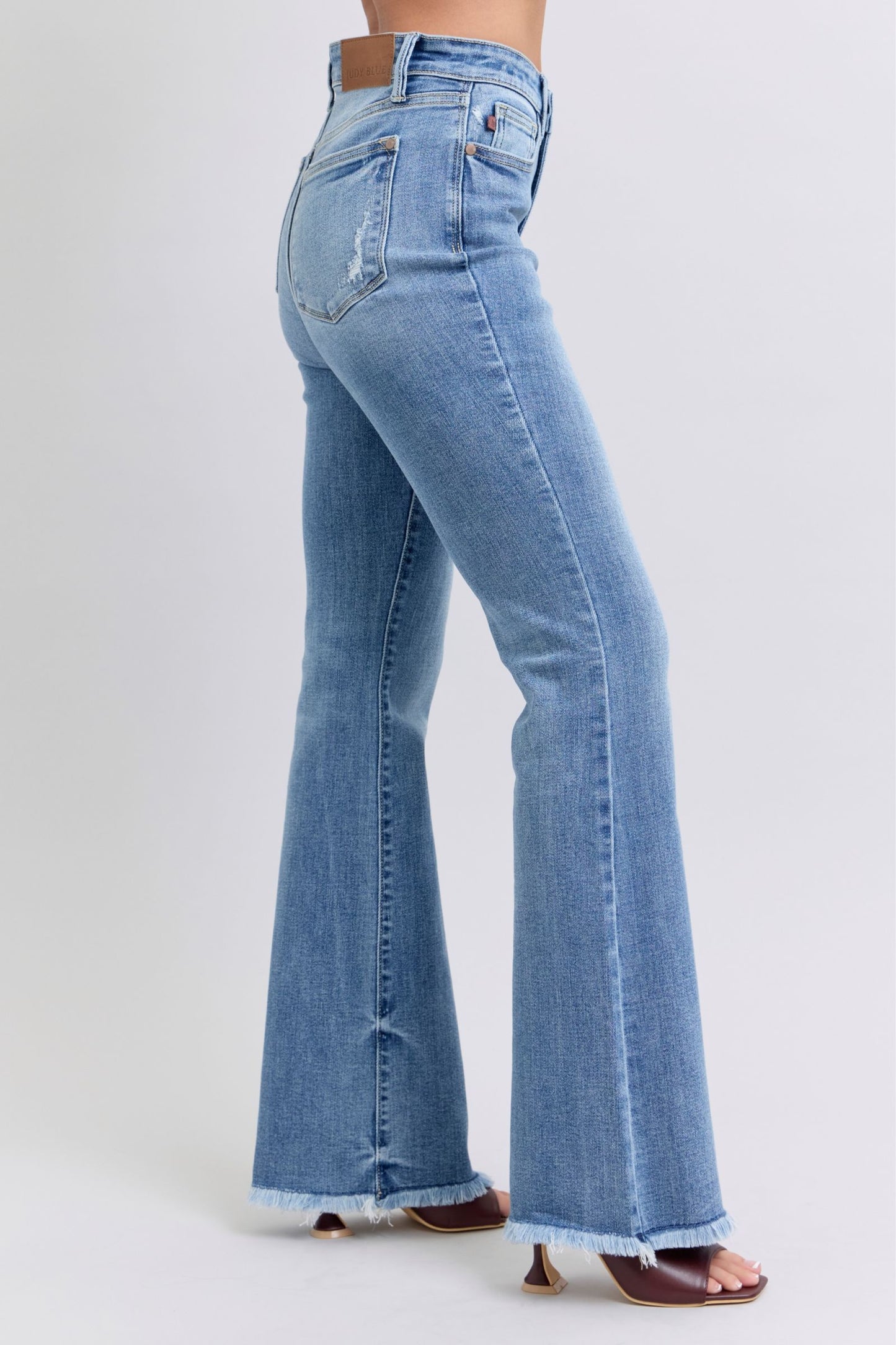 Side view of Judy Blue Raw Hem High Rise Bootcut Jeans highlighting the bootcut silhouette and raw hem detail.
