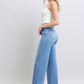 Judy Blue wide leg jeans styled on a model walking to highlight the flow of the wide-leg silhouette.
