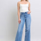 Styled outfit featuring Judy Blue wide leg jeans paired with a white crop top and sandals.
