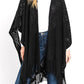 Front view of a black knitted fringe poncho, highlighting the open-knit design.