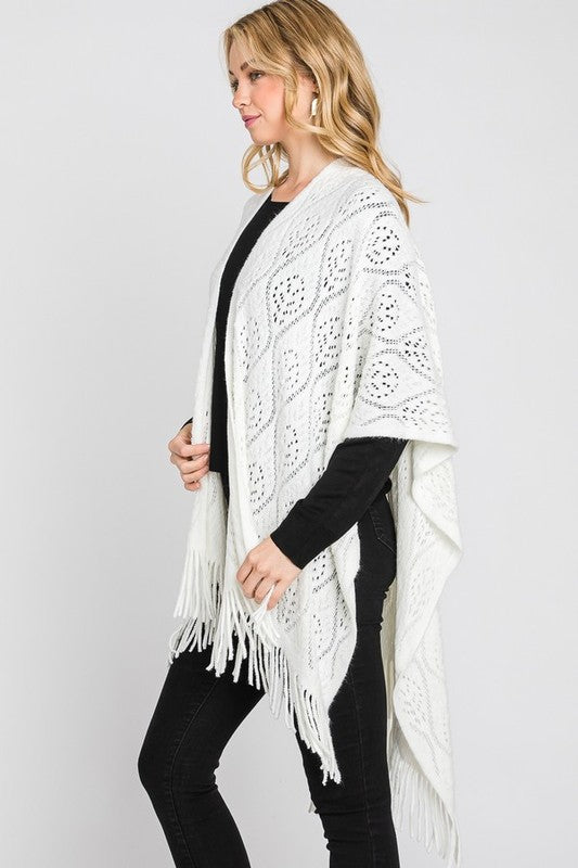 Detailed close-up of the open-knit pattern on the ivory poncho.