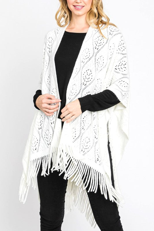 Front view of an ivory knitted fringe poncho, showing the open-knit texture.