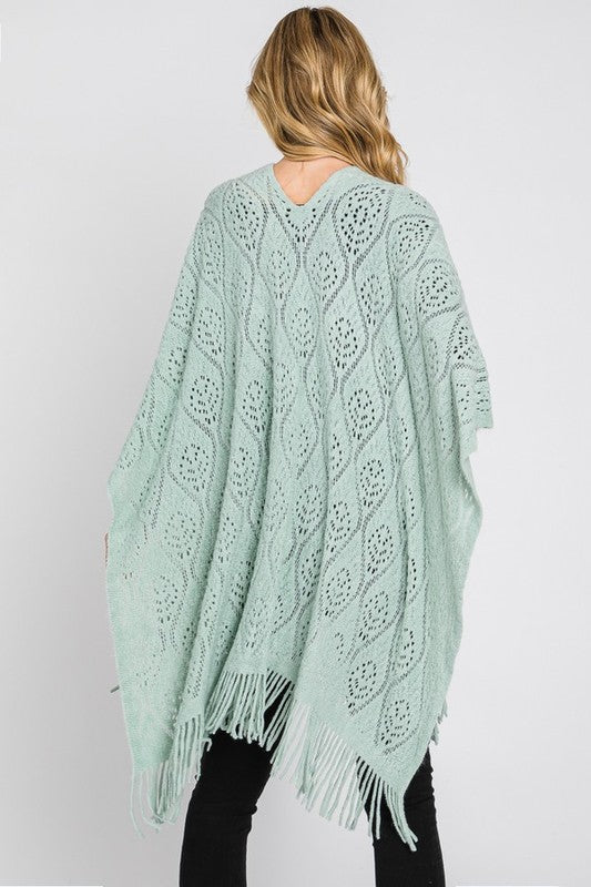 Fringe detailing on the mint green knitted poncho.