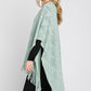 Fringe detailing on the mint green knitted poncho.