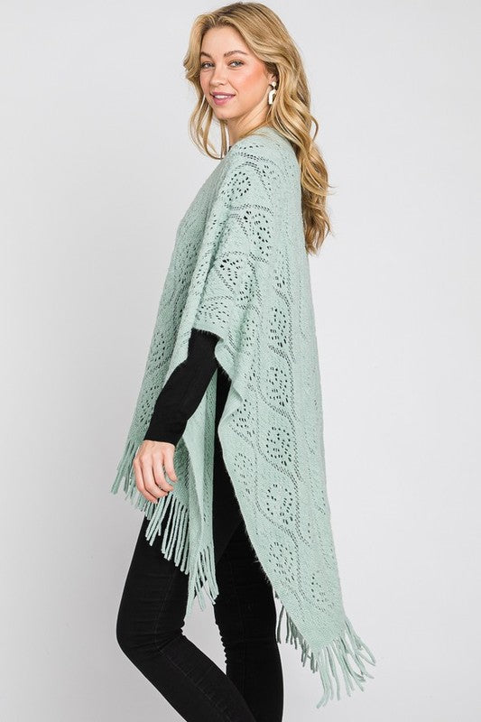 Fringe detailing on the mint green knitted poncho.