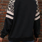 Black leopard-print pullover styled with contrast sleeve stripes for a trendy, casual vibe.