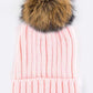 Light pink ribbed knit beanie with a fluffy faux fur pom, adding charm to any outfit.
