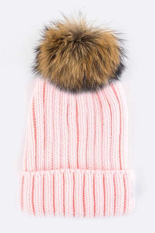 Light pink ribbed knit beanie with a fluffy faux fur pom, adding charm to any outfit.
