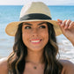 Close-up of a straw fedora hat with a black ribbon detail.