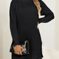 Woman wearing a cozy black turtleneck slit sweater.
