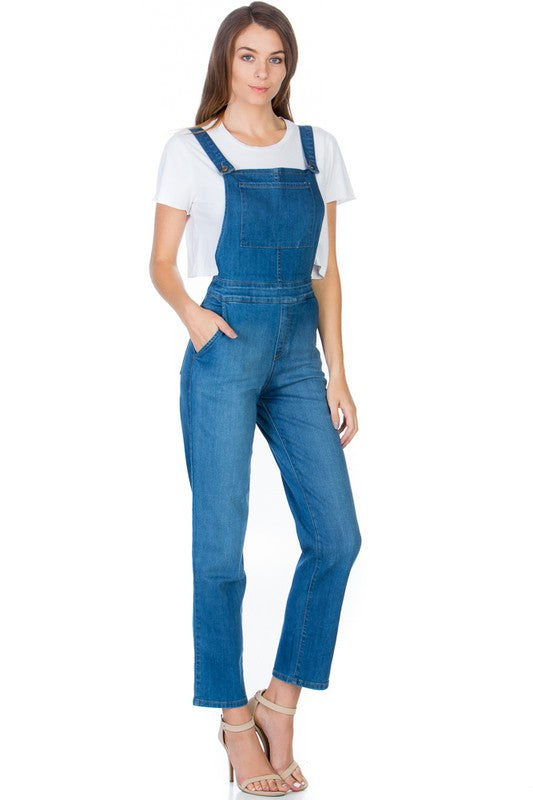 Side view of medium wash denim overalls showcasing functional pockets.
