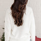 Back of the "Merry & Bright" white sweater with tinsel accents, great for casual or festive winter events.