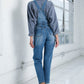 Adjustable shoulder straps on medium wash women’s denim jumpsuit.
