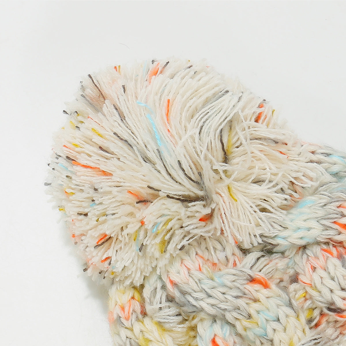 Beige multicolor knit pom-pom beanie with a soft, warm fit and colorful accents
