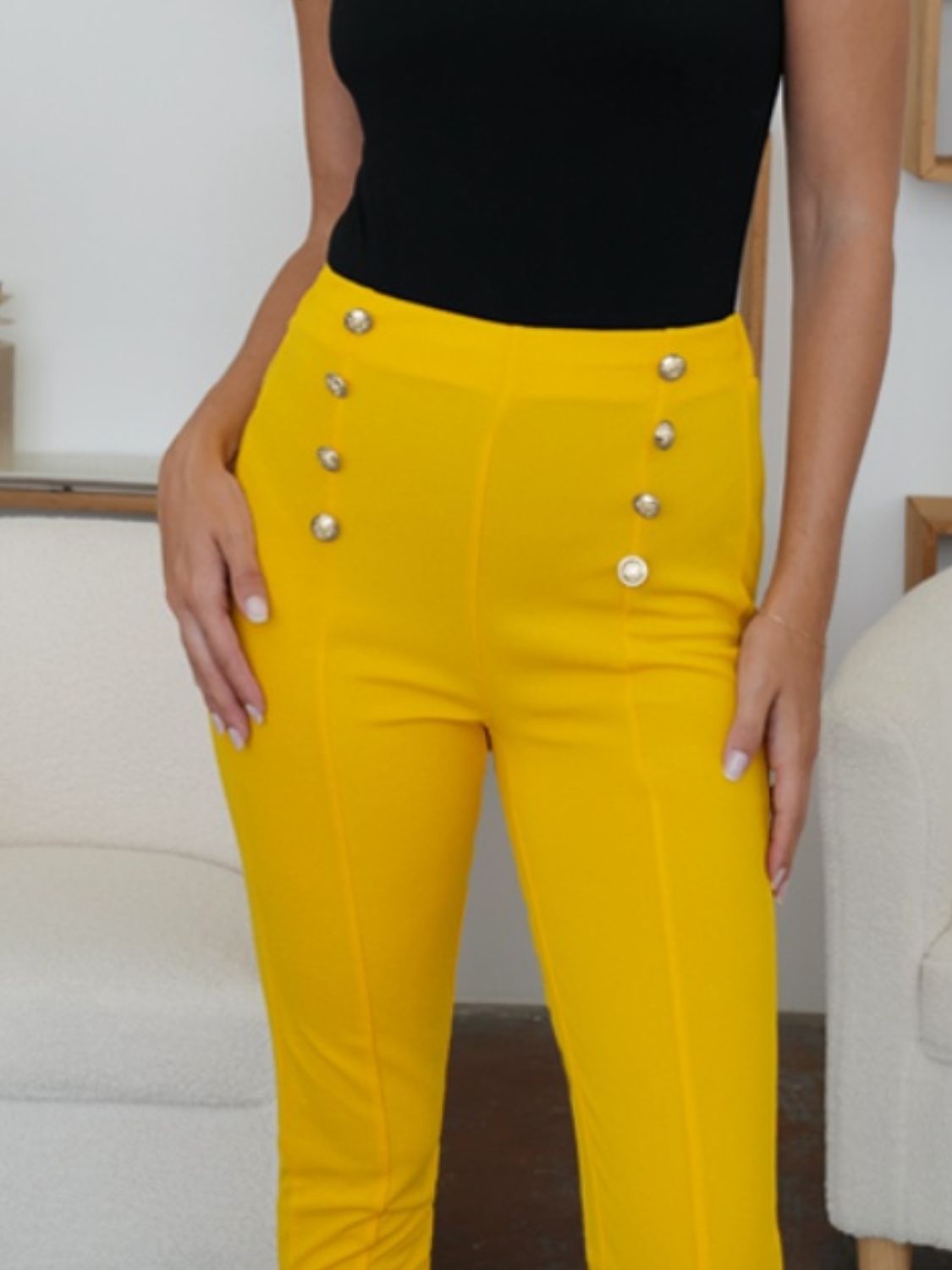 A pair of mustard high-waist pants with a chic, button-accented design.