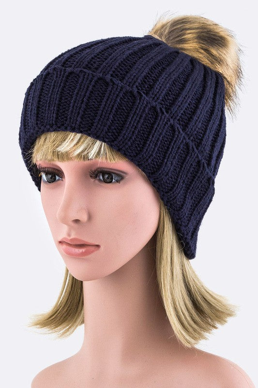 Navy ribbed knit winter hat topped with a fashionable faux fur pom.
