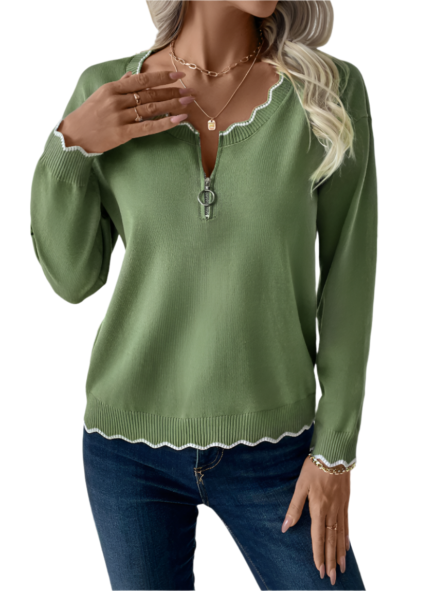 Woman wearing an olive green scalloped-edge zip-up sweater with jeans.
