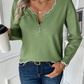 Green scalloped-edge knit sweater worn with denim for a relaxed yet chic outfit.
