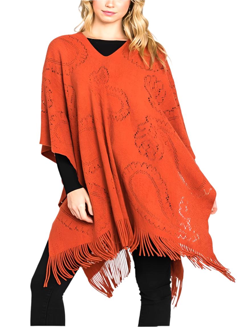 Orange paisley-pattern knit poncho styled over black outfit.
