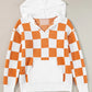 Orange and white checkered sweater with a hood, featuring a front pocket and long sleeves.
