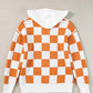 Orange and white checkered sweater with a hood, featuring a front pocket and long sleeves.
