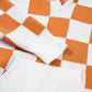 Orange and white checkered sweater with a hood, featuring a front pocket and long sleeves.
