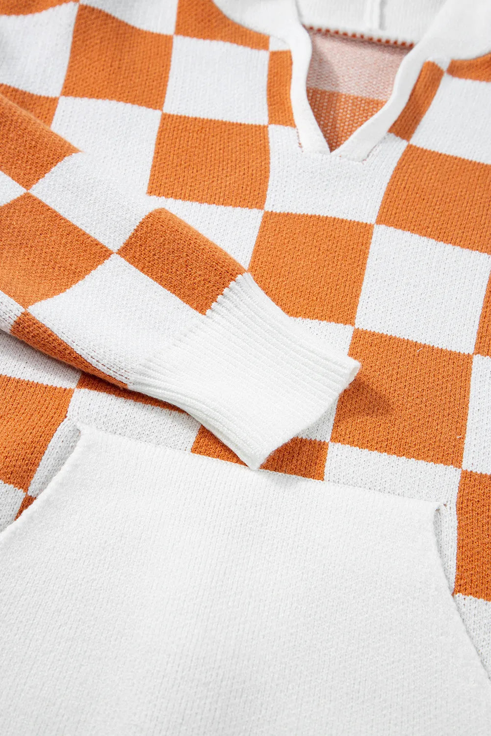 Orange and white checkered sweater with a hood, featuring a front pocket and long sleeves.
