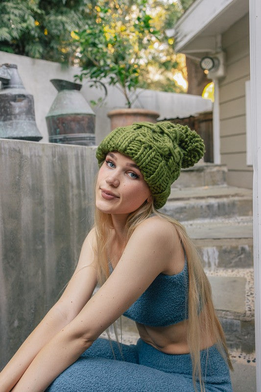 Cozy olive beanie featuring chunky yarn and coordinating pom detail

