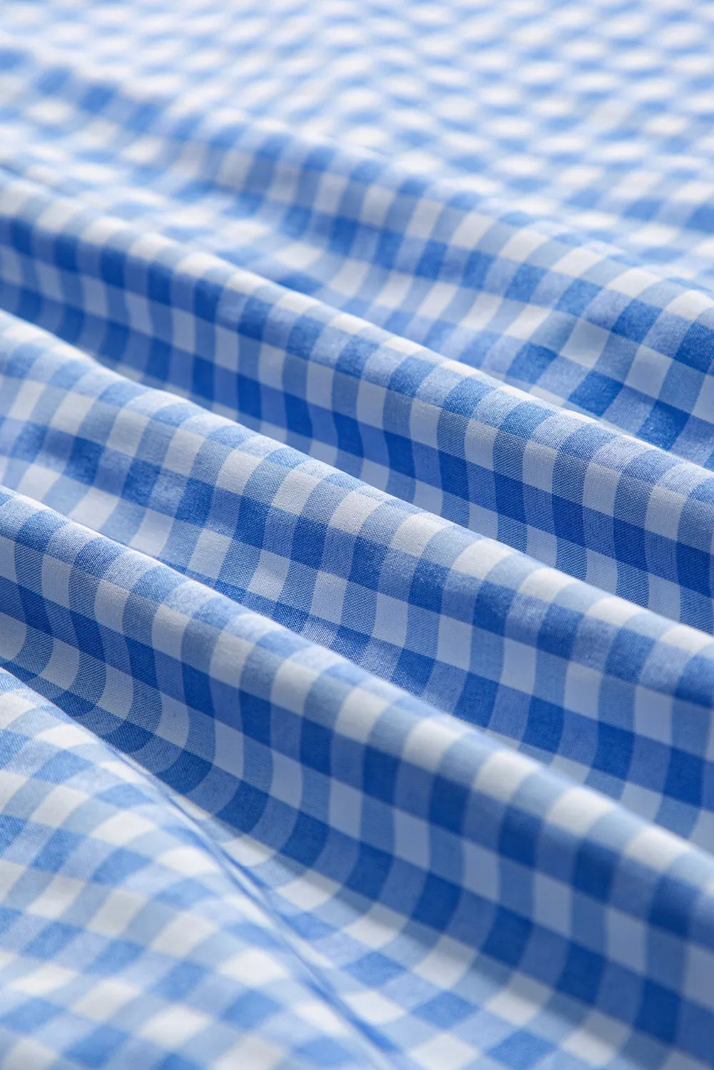 Close-up of women’s blue gingham shirt featuring a large front pocket
