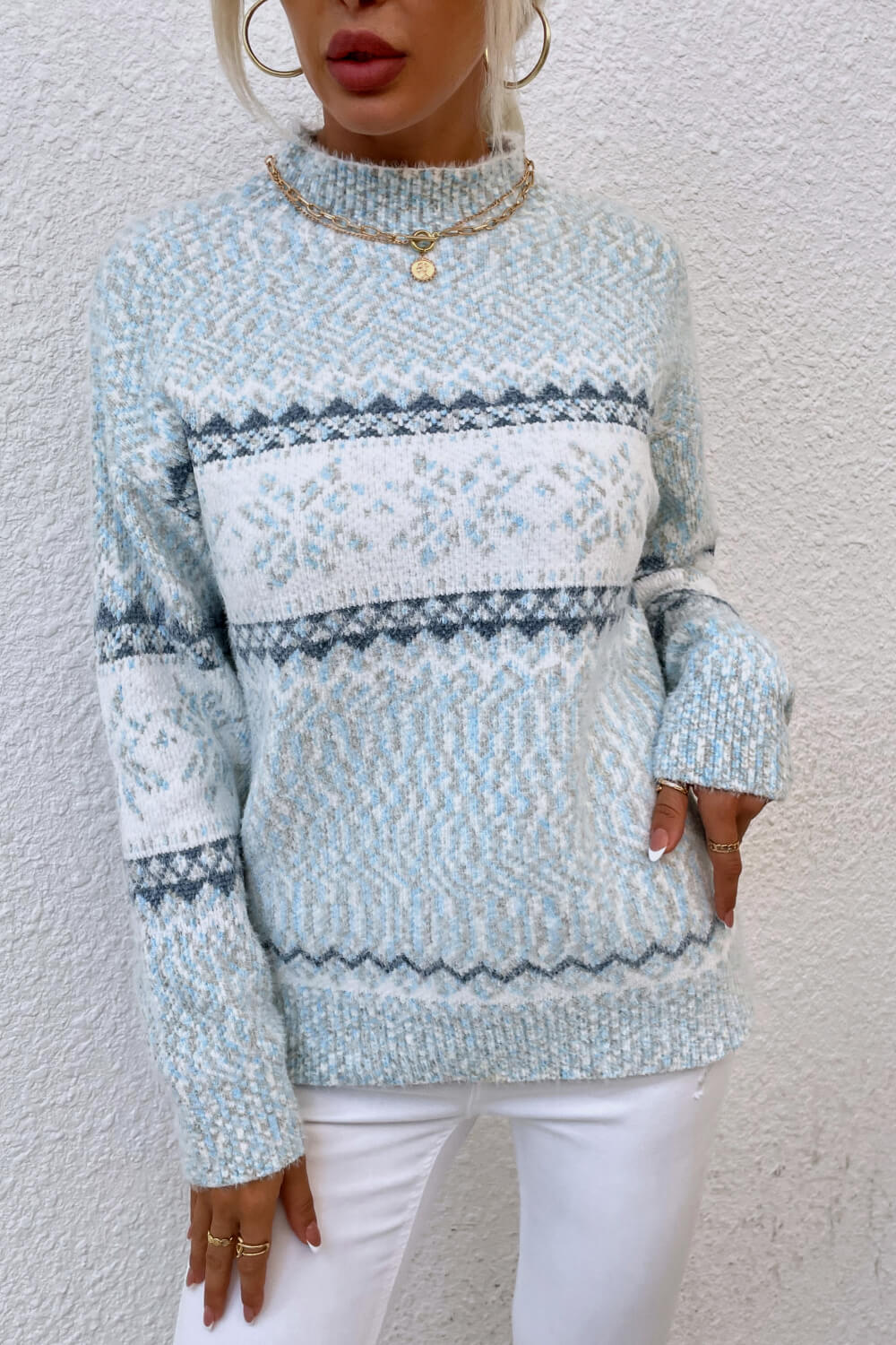 Pastel blue snowflake knit sweater with ribbed cuffs and hem, offering a soft, stylish winter look.

