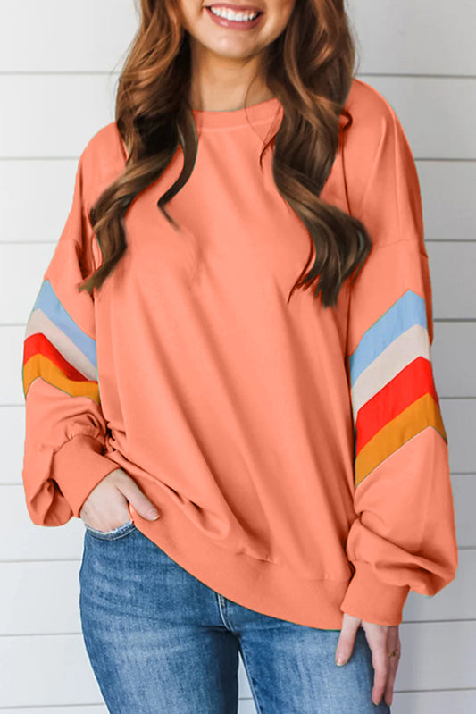 Casual chevron stripe sweatshirt in peach, featuring colorful sleeve details.
