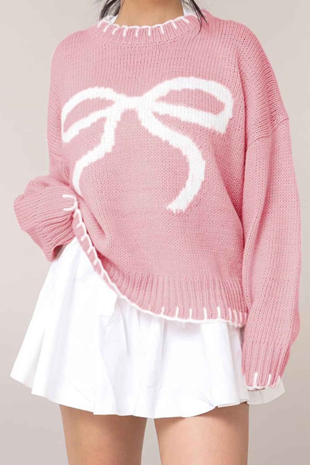 Front view of a pink bow-knot knit sweater, adding a playful element to your cozy winter outfits.