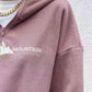 Pink-colored fleece sweatshirt with outdoor-inspired text.
