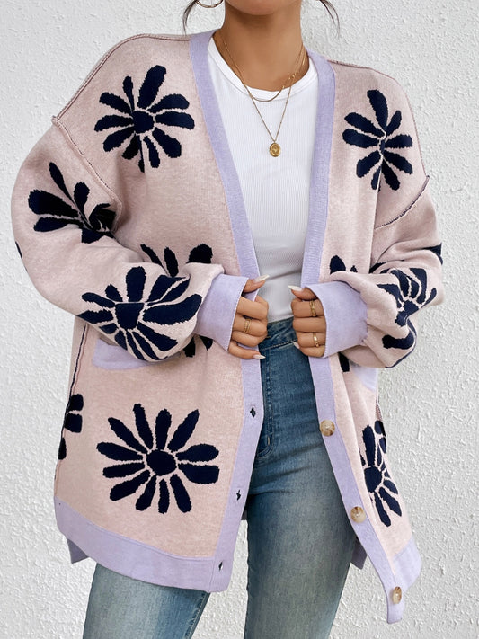 Close-up of a woman styling a pink floral cardigan over a white top and jeans.
