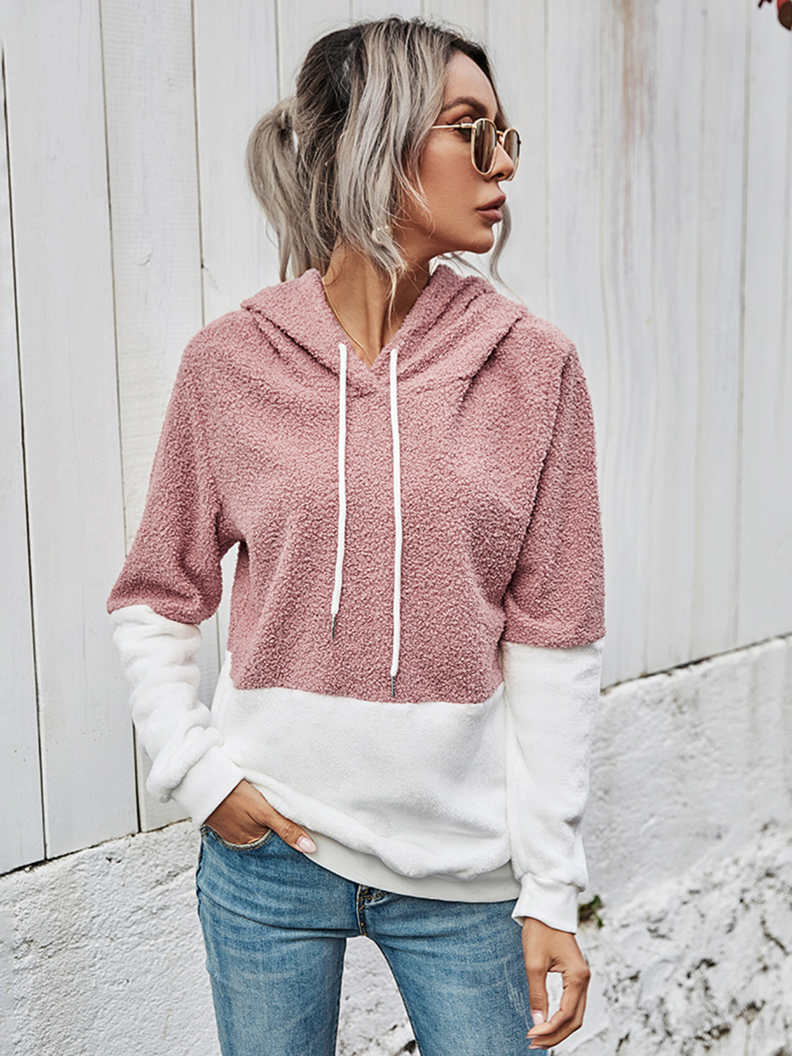 Front view of a pink sherpa hoodie with a white color block design.
