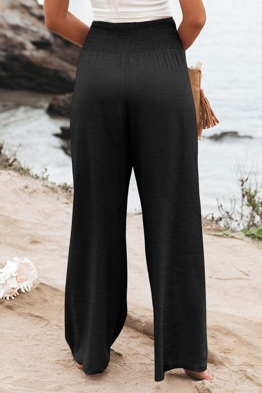 Black smocked high waist pants with flowy wide-leg fit for curves.