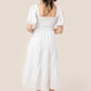 Smocked bodice whimsical white dress with puff sleeves and a square neckline.
