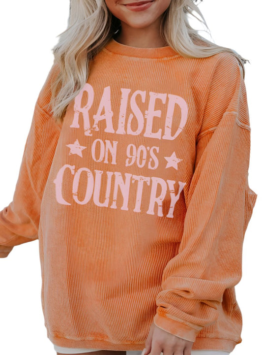 Front view of the Raised on 90's Country Graphic Sweatshirt in orange, showcasing the distressed graphic.