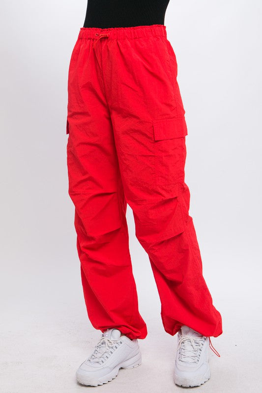 Red cargo pants featuring adjustable ankle fastenings and relaxed silhouette.
